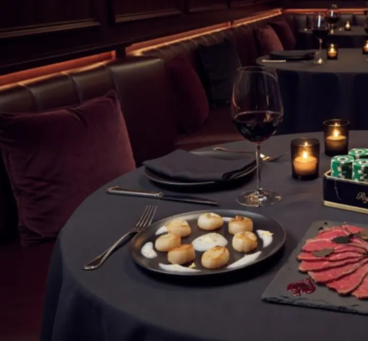Elegáns fine dining tálalás gyertyafényes, kártyalapokkal díszített asztalon a WIN REVIEW SPACE-ben.